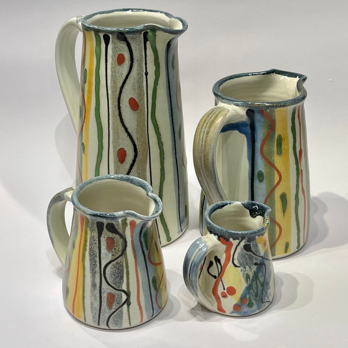 A set of four hand-painted ceramic jugs by Lea Phillips